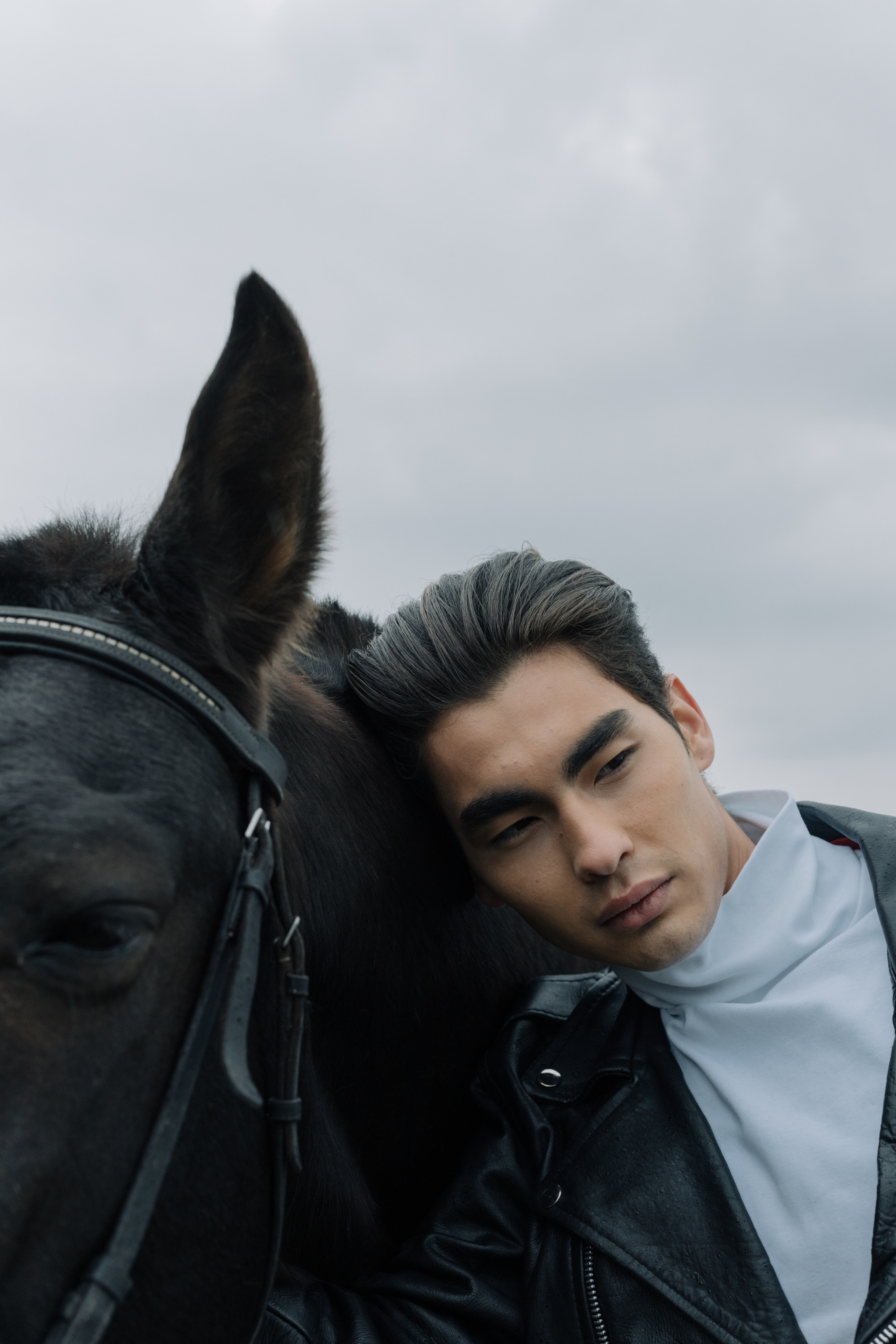 A Man  Standing Beside a Black Horse