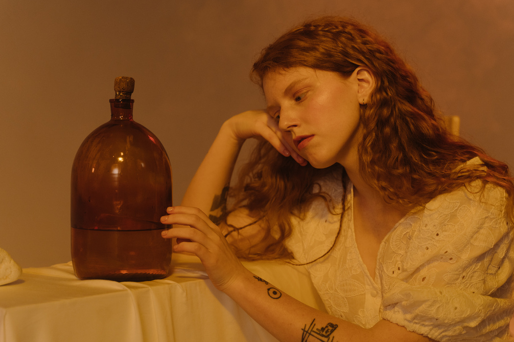 Woman in White Dress Holding a Glass Container