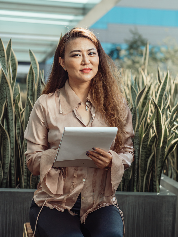 Photo of a Woman with Brown Hair Looking at the Camera while Holding a Paper Pad